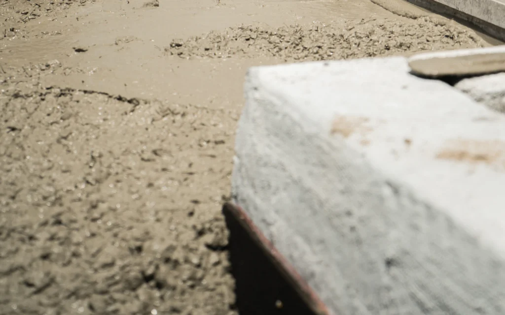 Worker placing new concrete across a deck slab during a parking garage restoration